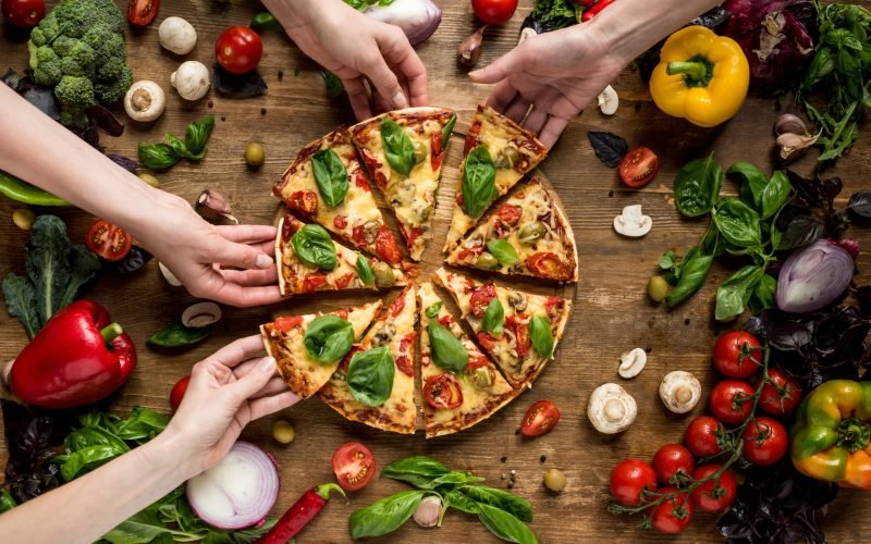 partial view of friends taking homemade pizza slices